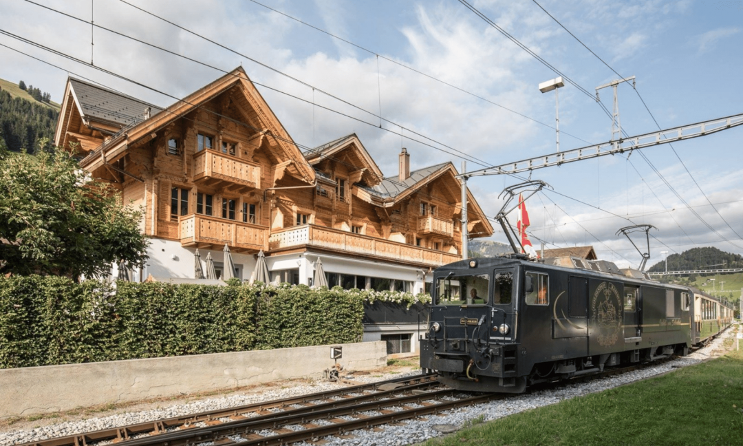 View of the Valrose Hotel next to the train station and train on the track - no season - Rougemont - Valrose