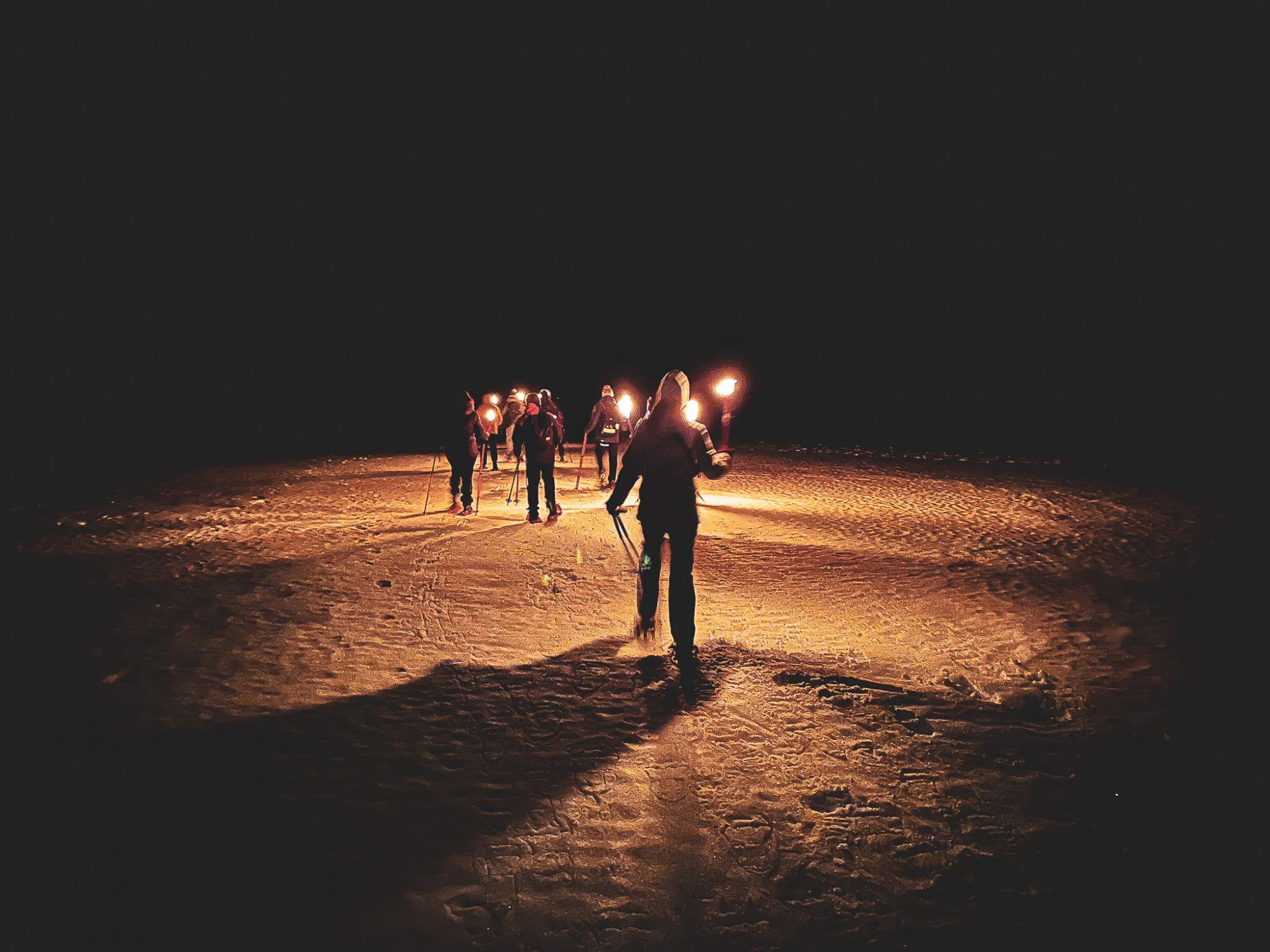 Setting out on the frozen lake at night by torchlight