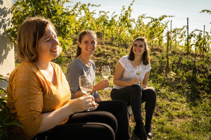 Winzerin Laura Paccot mit 2 Gaesten beim Degustieren in einem Rebberg der Domaine de La Colombe.