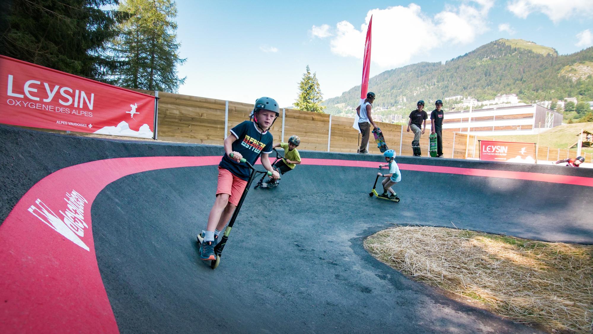 Kind auf Motorroller auf der Pumptrack - Leysin - Sommer
